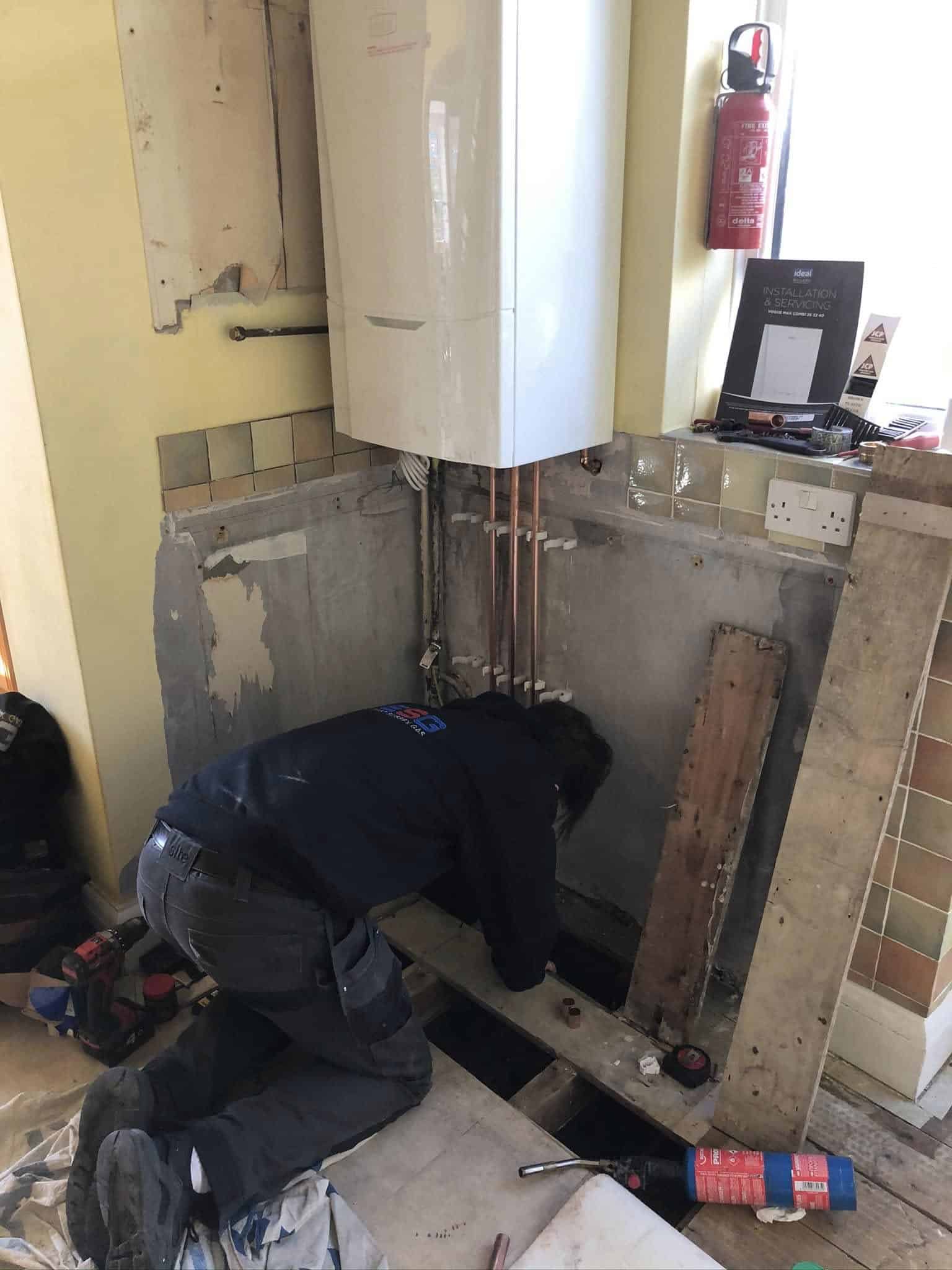 Engineer from East Sussex Gas working beneath a wall-mounted boiler during an installation project