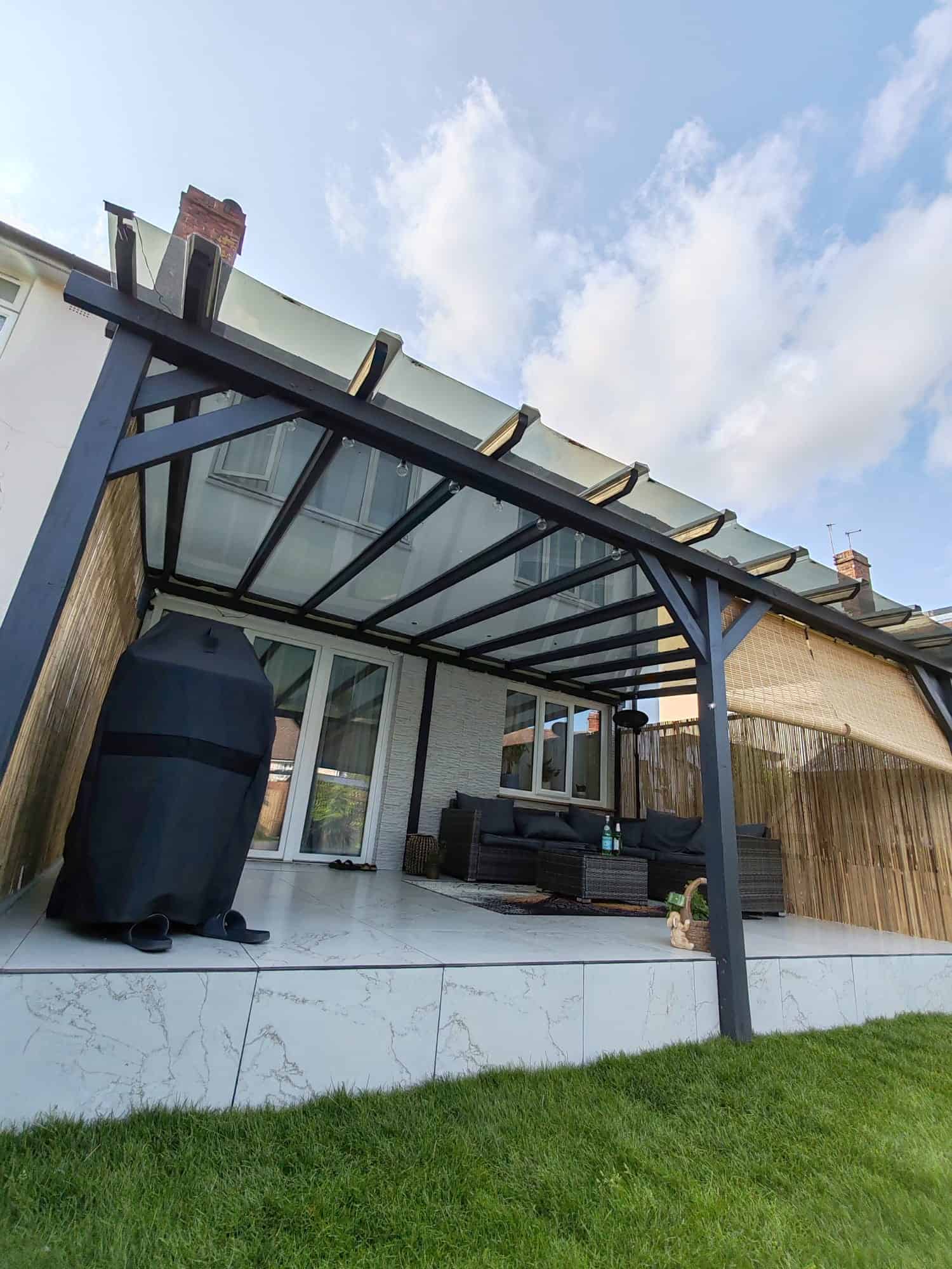 Modern glass roof pergola attached to a house above a paved patio seating area