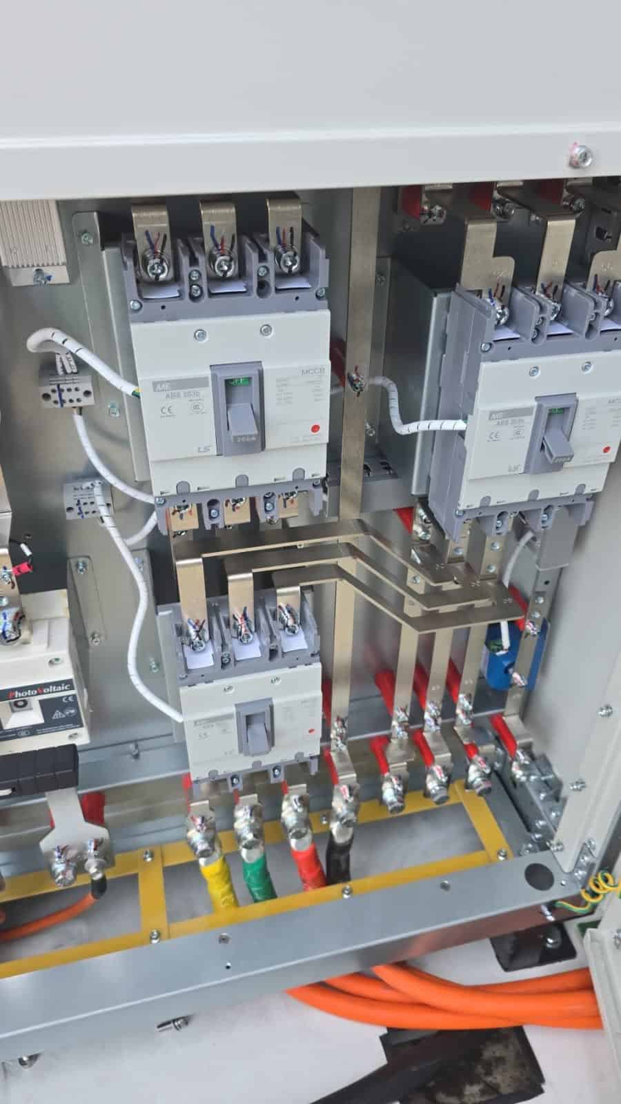Internal view of an electrical distribution panel with breakers, busbars and power cables.