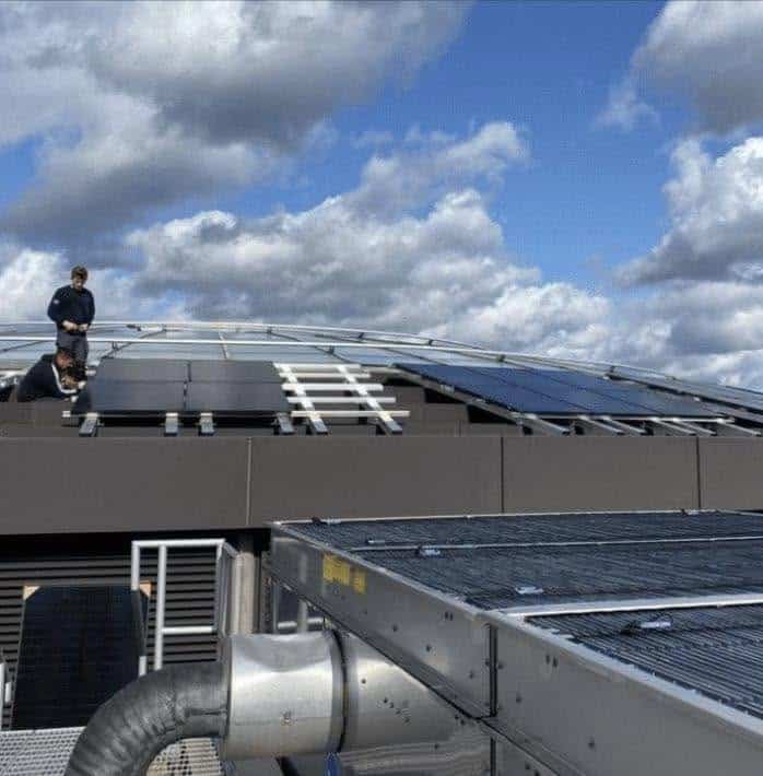 Engineers installing solar panels on a rooftop commercial building.