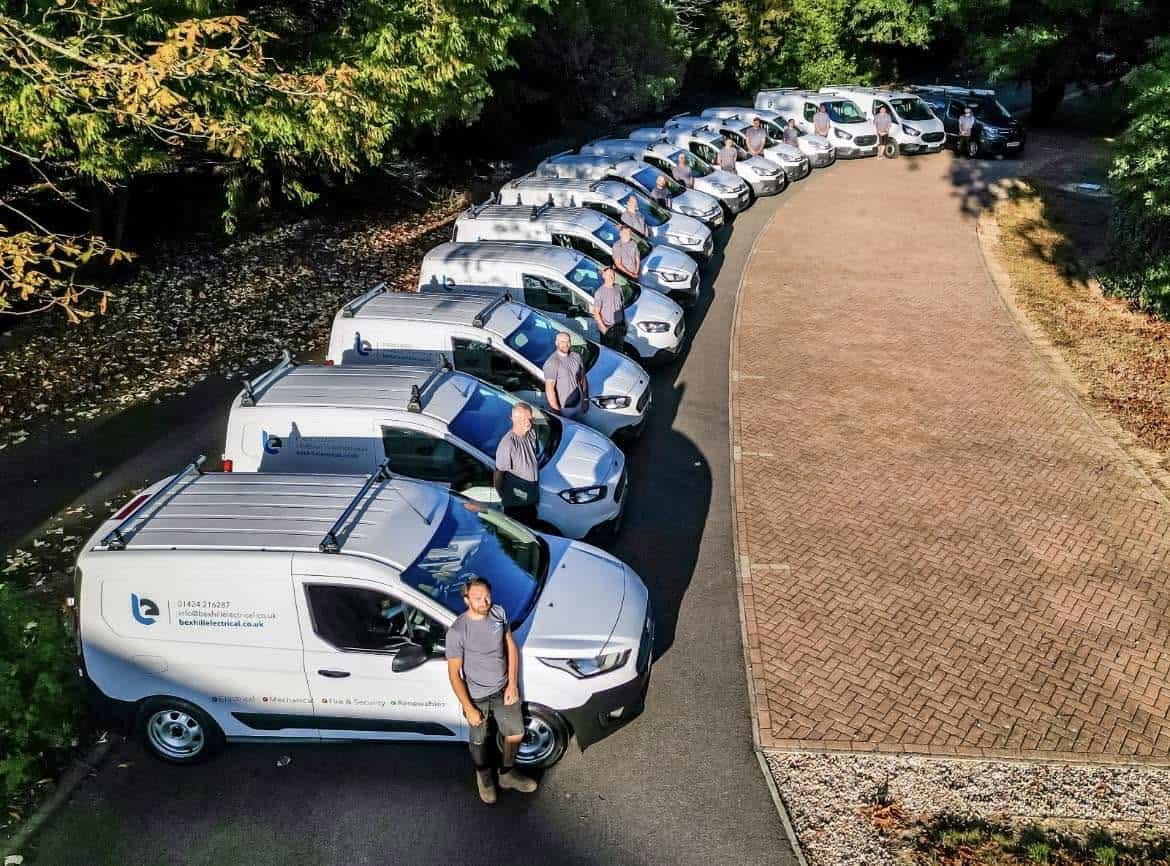 Bexhill Electrical engineers standing beside a fleet of company service vans.