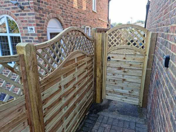 Timber garden gate with matching lattice fence panels installed between two brick houses in Bexhill