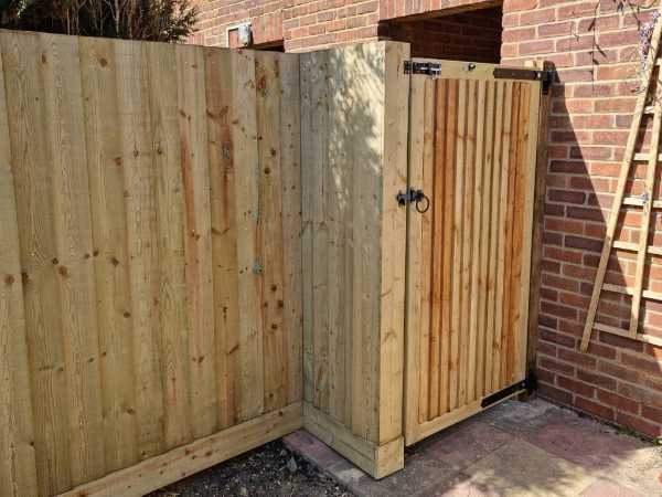 Timber side gate with matching privacy fence panels installed beside a brick property in Bexhill