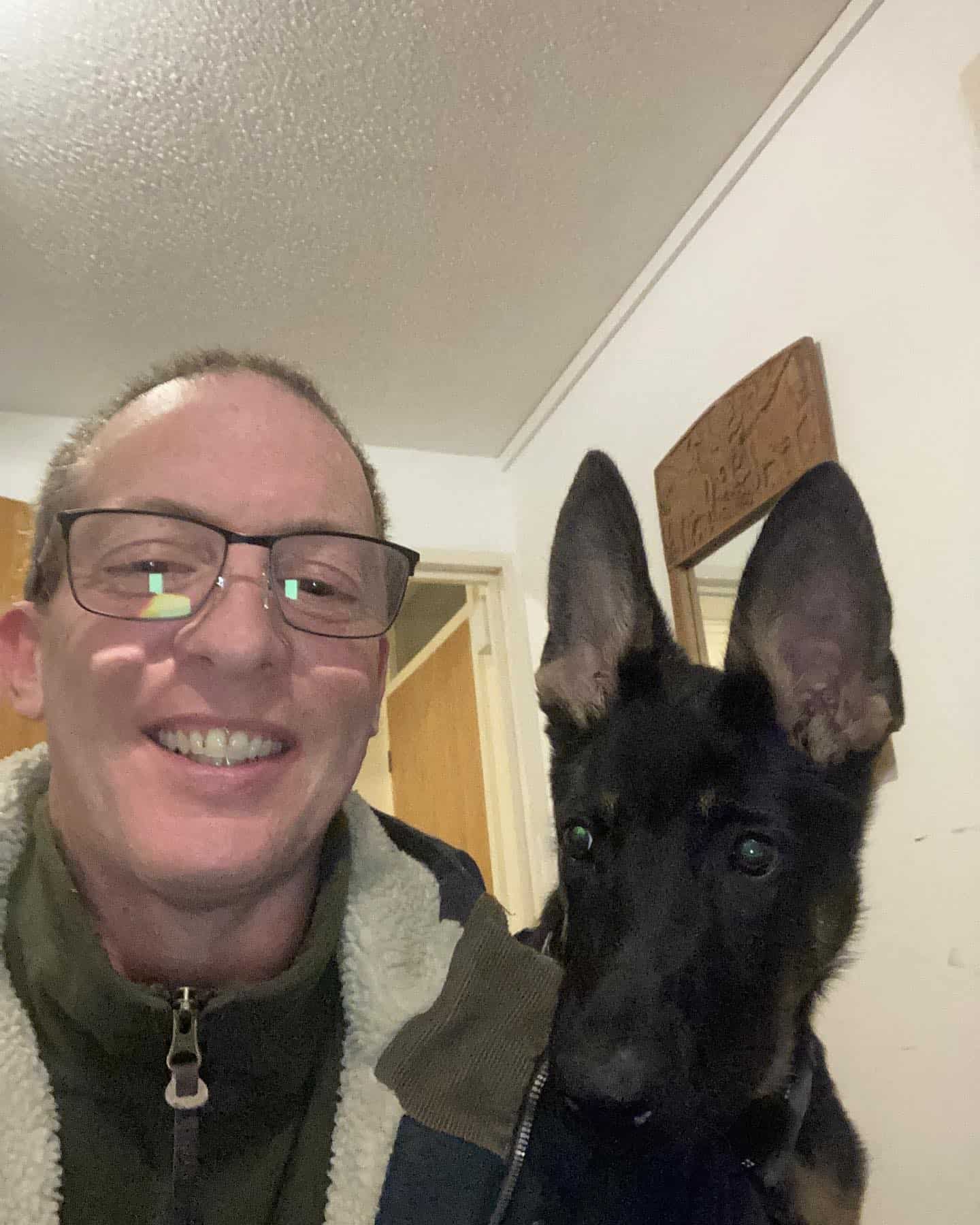 Owner of Roma's Dog Training smiling alongside a young German Shepherd dog indoors