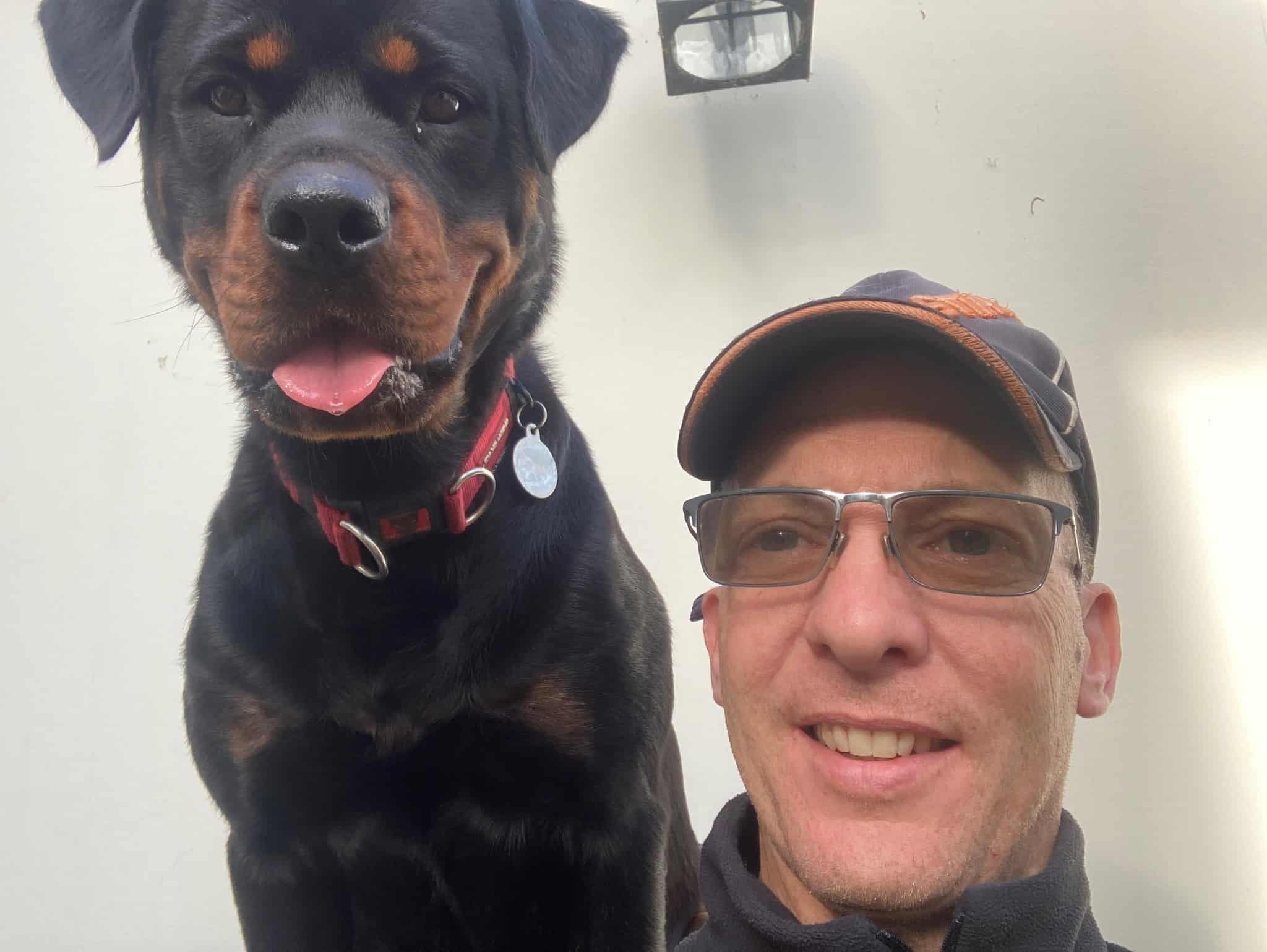 Owner of Roma's Dog Training posing with a Rottweiler wearing a red collar