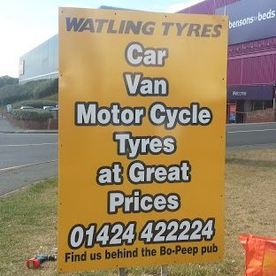 Yellow roadside sign advertising car, van and motorcycle tyres at Watling Tyres in Hastings.
