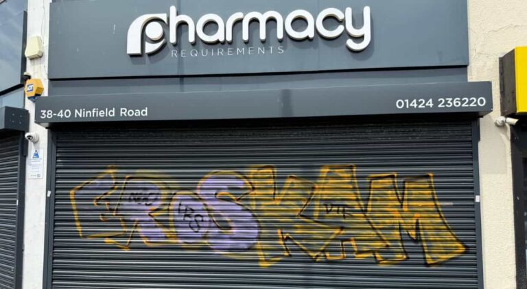 Graffiti sprayed across the metal security shutters of Pharmacy Requirements in Sidley following overnight vandalism.